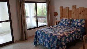 a bedroom with a bed with a blue blanket and a window at Jardim Azul Praia in Pitimbu