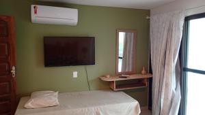 a bedroom with a bed and a flat screen tv at Jardim Azul Praia in Pitimbu