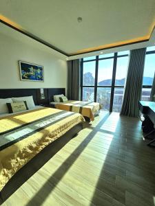 a hotel room with two beds and large windows at La Maison in Cat Ba