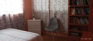 ein Schlafzimmer mit einem Bett und einem Stuhl neben einem Bücherregal in der Unterkunft Departamento 5p Tierra del Sol Eterno - Ica centro in Ica