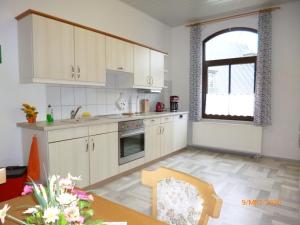 a kitchen with white cabinets and a table and a window at Ferienwohnung Im Vierseitenhof in Annaberg-Buchholz