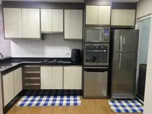 Una cocina con gabinetes blancos y electrodomésticos de acero inoxidable. en Banheiro INDIVIDUAL, Garagem Coberta e TV com streamings, en Campo Mourão