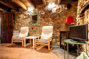 ein Wohnzimmer mit zwei Stühlen und einem Fernseher in der Unterkunft Ruralmedulas Casa 2 in La Campañana