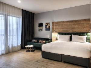 ein Schlafzimmer mit einem großen Bett und einer Couch in der Unterkunft Tarcin Forest Resort & Spa Sarajevo - MGallery Collection in Tarčin