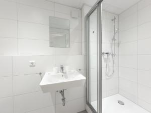a white bathroom with a sink and a shower at C&M Hotel in Hamburg