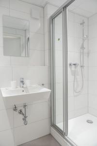 a white bathroom with a shower and a sink at C&M Hotel in Hamburg