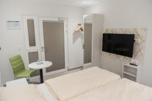 a bedroom with two beds and a tv and a chair at C&M Hotel in Hamburg