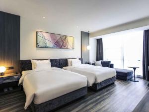 a hotel room with two beds and a large window at Mercure Shanghai Hongqiao South in Shanghai