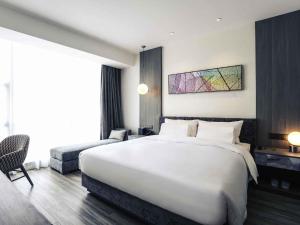 a hotel room with a large white bed and a couch at Mercure Shanghai Hongqiao South in Shanghai