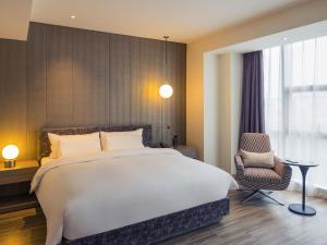 a bedroom with a large bed and a chair at Mercure Shanghai Hongqiao South in Shanghai
