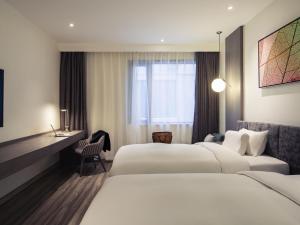 a hotel room with two beds and a desk at Mercure Shanghai Hongqiao South in Shanghai