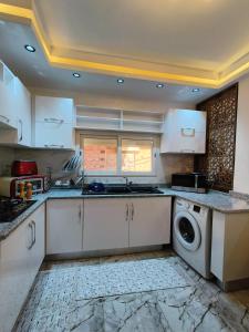a kitchen with white cabinets and a washing machine at Dar El Ommda in Tozeur +4 photos