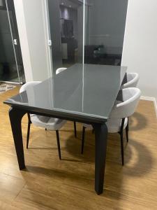 une table à manger en verre avec des chaises blanches autour dans l'établissement Quarto Em Sobrado - Banheiro INDIVIDUAL, Garagem Coberta e TV com streamings, à Campo Mourão