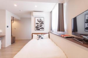 Dieses weiße Zimmer verfügt über ein Bett und einen TV. in der Unterkunft LANG HOTEL Kameido - Vacation STAY 79258v in Tokio