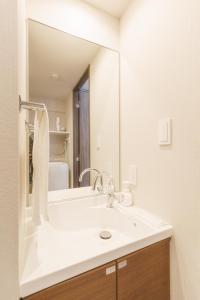 LANG HOTEL Kameido - Vacation STAY 79286v في طوكيو: حمام مع حوض ومرآة كبيرة +8 صور