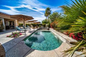 a swimming pool in a backyard with an umbrella at Luxurious Custom-built Villa Pool Spa Fire Pit more in Palm Desert