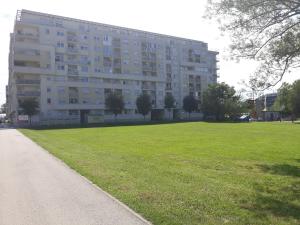 a large building with a grassy field in front of it at Lux Apartmans in Zagreb
