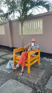 a man sitting on a bench drinking a cup of coffee at Casa Tranquila Airpot Transit Stay in Dar es Salaam