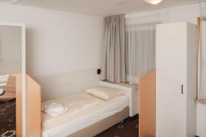 a small room with a bed and a mirror at C&M Hotel in Hamburg