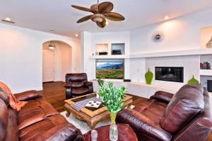a living room with leather furniture and a ceiling fan at Poolside Bliss with elegant living #1 Rated in Palm Desert