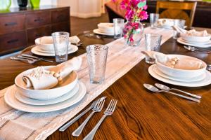 a table with plates and silverware on a wooden table at Poolside Bliss with elegant living #1 Rated in Palm Desert