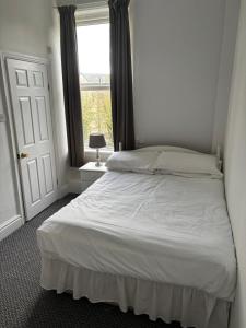 a bedroom with a white bed with a window at ashwood hotel in Preston +3 photos