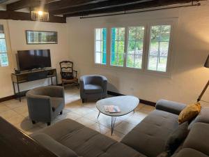 a living room with a couch and chairs and a tv at Les grandes bruyères in Lesperon