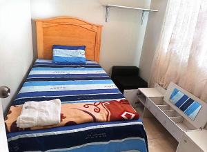 une petite chambre avec un lit et une tête de lit en bois dans l'établissement Casa en Lambayeque, à Lambayeque