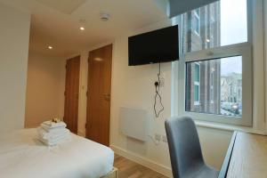 a hotel room with a bed and a television on the wall at Studio Flat Close to Queen Square - Flat 4A in Bristol