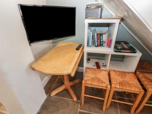 a small desk with a tv and a table and chairs at Tyg Cottage in Grewelthorpe
