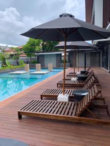 eine Gruppe von Liegestühlen mit einem Sonnenschirm neben einem Pool in der Unterkunft Villa Bun Blessi in Pesanggaran