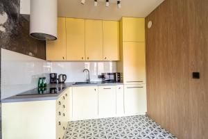a kitchen with yellow cabinets and a tile floor at SPA Waterlane Island Deluxe 1 by Grand Apartments in Gdańsk