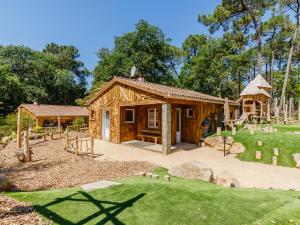 a log cabin with a playground in a yard at Flower Camping Au Bois des Biches in Saint-Hilaire-de-Riez