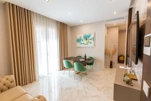 ein Wohnzimmer mit einem Tisch und grünen Stühlen in der Unterkunft Ginex Luxury Suite, Trani in Trani