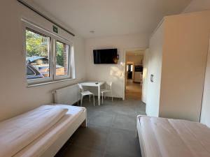 ein Zimmer mit zwei Betten und einem Tisch und einem Fenster in der Unterkunft OWL Comfort Homes - Porta Westfalica in Porta Westfalica