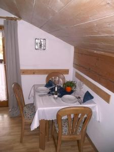 a dining room table with a white table cloth and chairs at Dachgeschosswohnung Mit Toller Aussicht Vom Balkon in Bayersoien
