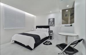 Un dormitorio blanco con una cama y una mesa. en aiden, en Busan 17 fotos más