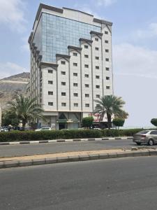 ein großes weißes Gebäude mit Palmen davor in der Unterkunft فندق مسار الأمل الذهبي - أثمان سابقاً in Al ‘Azīzīyah