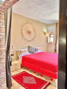 a bedroom with a red bed and a red rug at Argana by Maj Nia - Jardin - Piscine - Luxe - 3 Px in Bou Zemmour