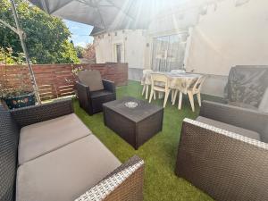 a patio with wicker furniture and a table and chairs at Maison de village à Puybrun in Puybrun