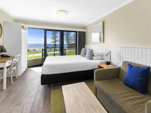 a hotel room with a bed and a couch and a table at ibis Styles Port Macquarie in Port Macquarie