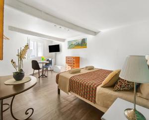 a bedroom with a bed and a desk and a table at Les Amandiers - L'Isle d'Or in LʼIsle-sur-la-Sorgue