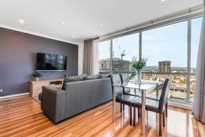 a living room with a couch and a table with chairs at Adelaide Central Skyline Panoramic Suite One in Adelaide