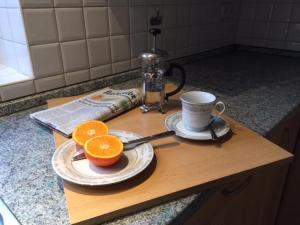 a cutting board with two oranges and a cup on it at Ferienwohnung Ruheoase In Otterndorf in Otterndorf