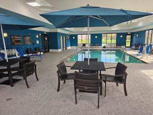 a pool with tables and chairs and a large blue umbrella at Hampton Inn & Suites Marshalltown in Marshalltown