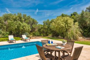 a patio with a table and chairs next to a swimming pool at Villa Mig Coster - Refugio rural en finca privada in Sant Lluis