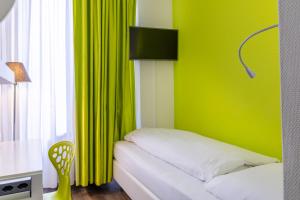 a room with a bed and a green wall at Hotel City Inn Basel in Basel