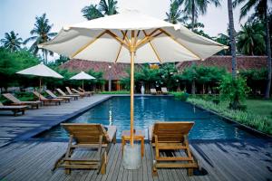 a table and chairs with an umbrella next to a pool at Royal Regantris Villa Karang in Gili Air