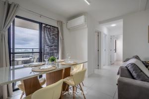 a kitchen and living room with a table and a couch at Estadia completa com piscina e academia a 400m da Praia da Armação - SKL in Penha