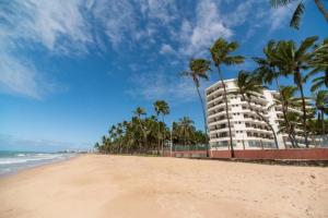 a view of a beach with palm trees and a building at Jatiúca Suítes Resort - Flat 413 in Maceió